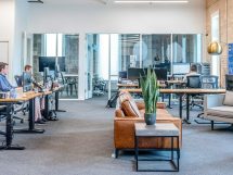 man in blue dress shirt sitting on rolling chair inside room with monitors