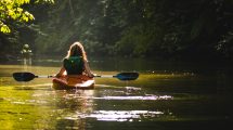 woman on kayak on body of water holding paddle