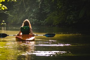 woman on kayak on body of water holding paddle
