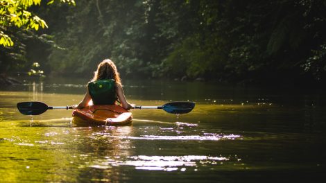 woman on kayak on body of water holding paddle