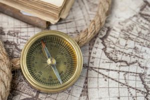A close-up of a vintage compass on an antique world map, depicting navigation history.