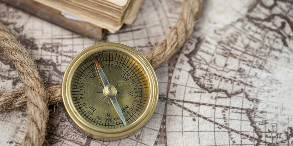 A close-up of a vintage compass on an antique world map, depicting navigation history.