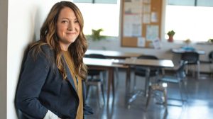 woman in black coat standing in classroom
