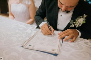 Groom signing marriage certificate with bride beside him