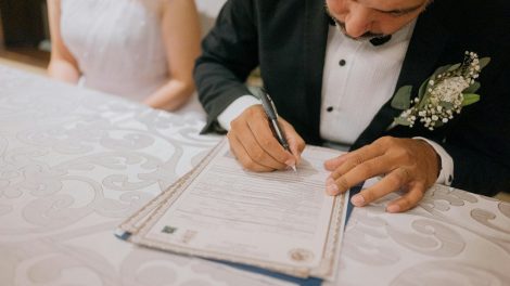 Groom signing marriage certificate with bride beside him